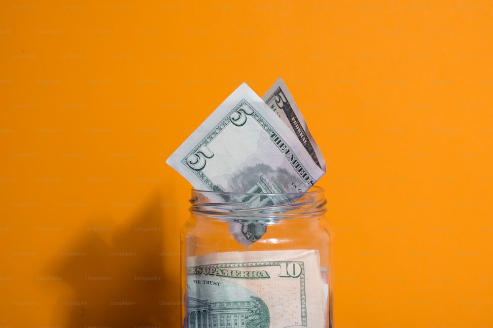 a glass jar filled with money sitting on top of a table