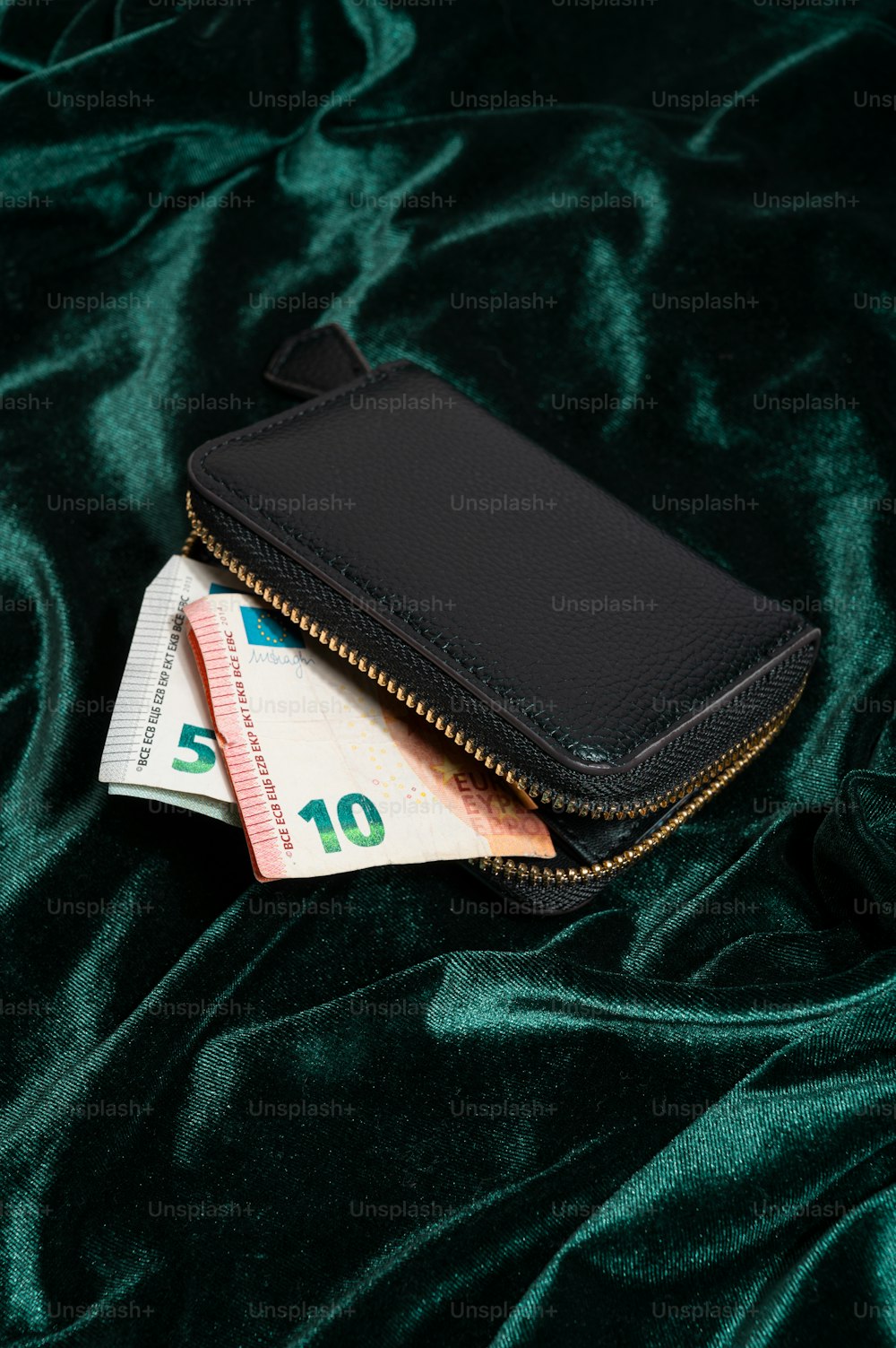 a black wallet sitting on top of a green blanket