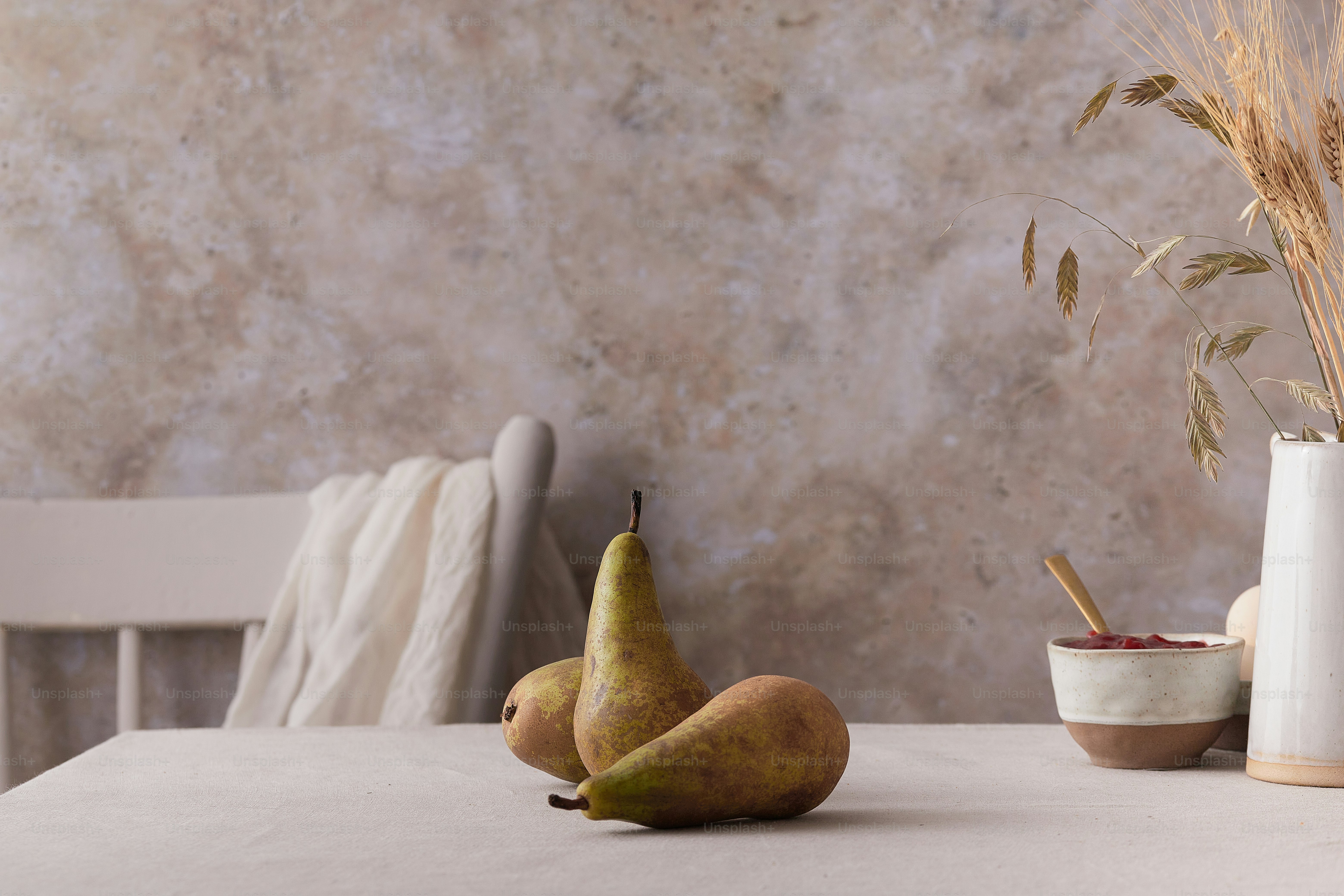 a table topped with two pears and a white vase