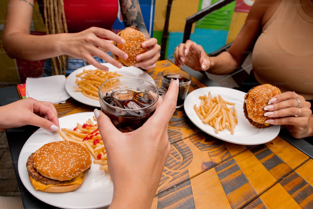 a group of people sitting at a table eating hamburgers and fries