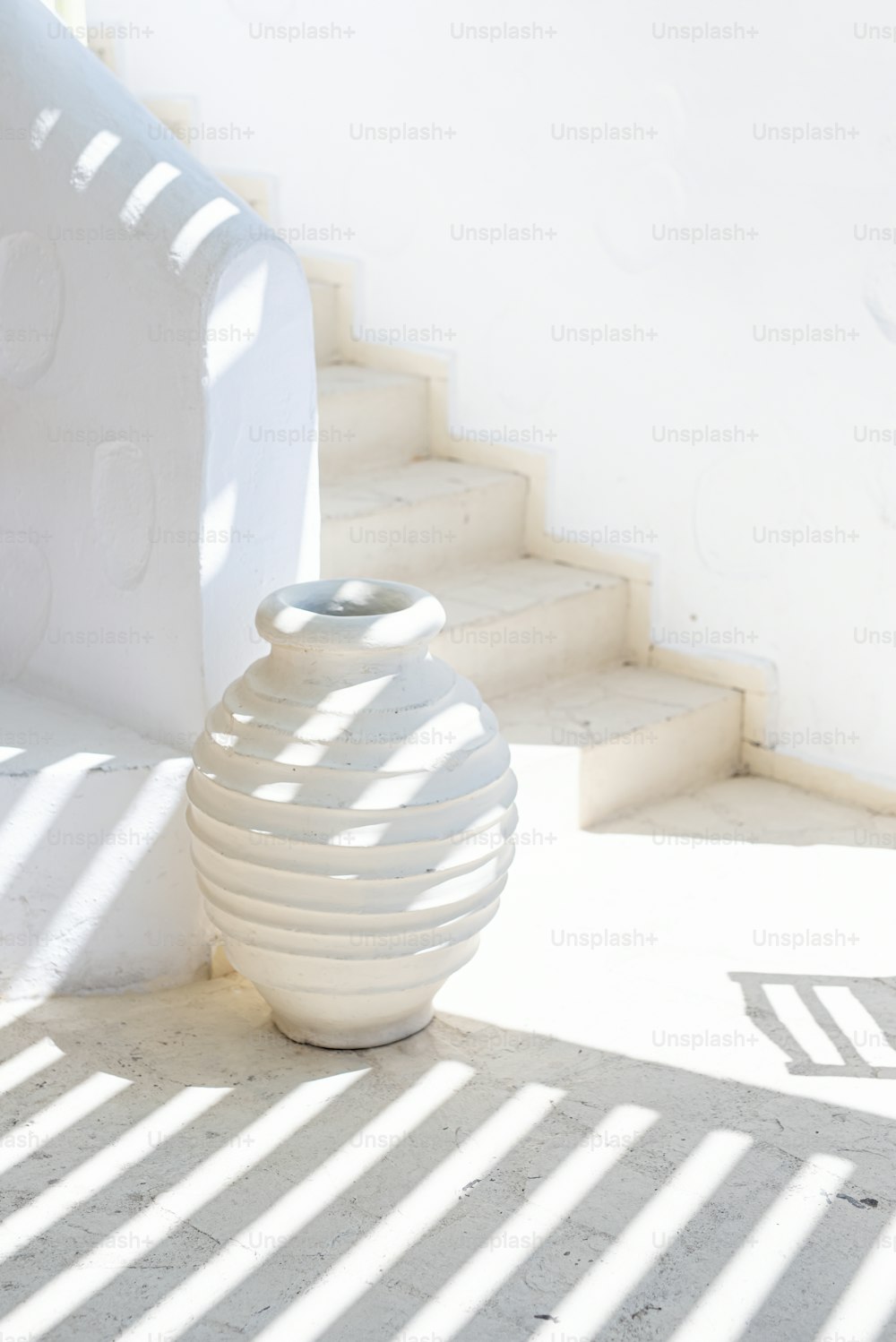 a white vase sitting on the ground next to some stairs