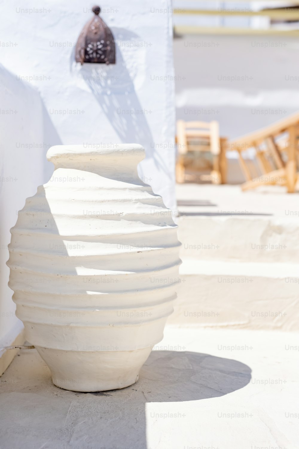 un vaso bianco seduto accanto a un muro bianco