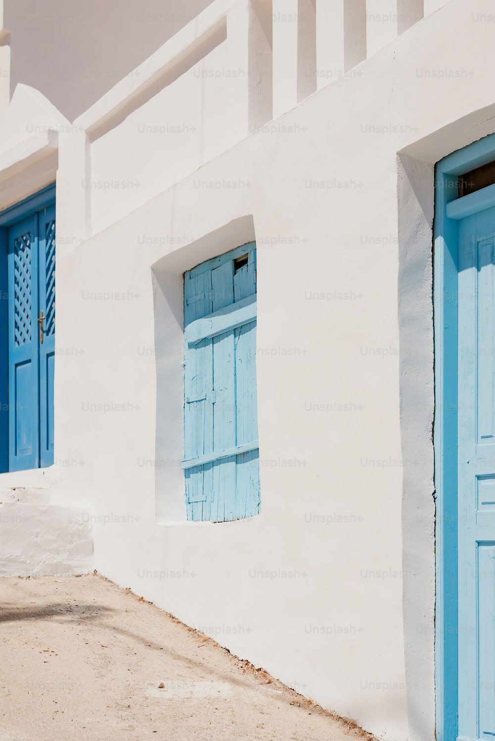 Ein weißes Gebäude mit blauen Fensterläden und einem roten Hydranten