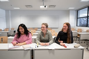 Tres mujeres sentadas en pupitres en un aula