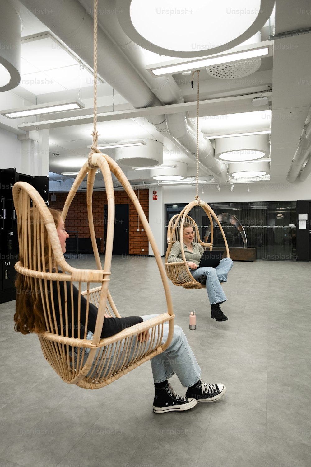a woman sitting in a swing chair in a large room