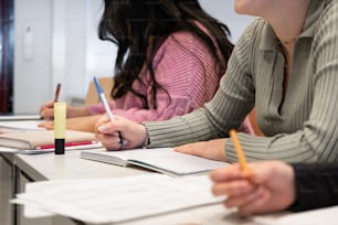 a group of people sitting at a table with notebooks and pens