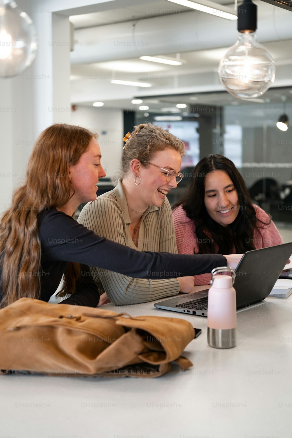 a group of women sitting at a table looking at a laptop