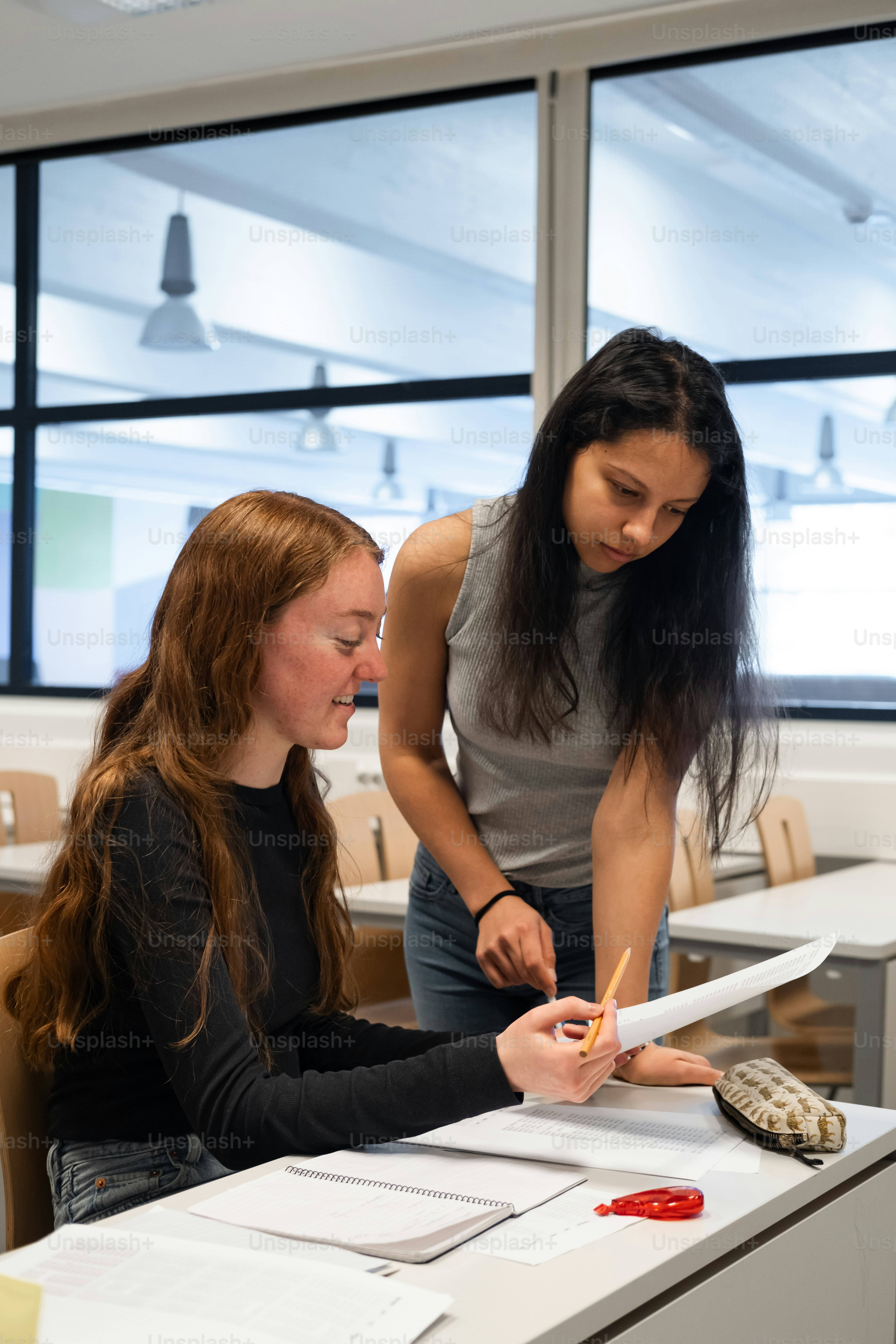 two women sitting at a table with a pen and paper