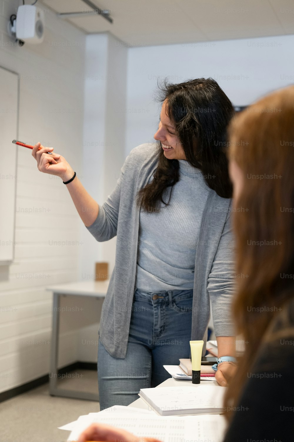 a woman standing in front of a whiteboard pointing at something