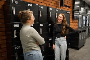 two women standing in front of a row of lockers