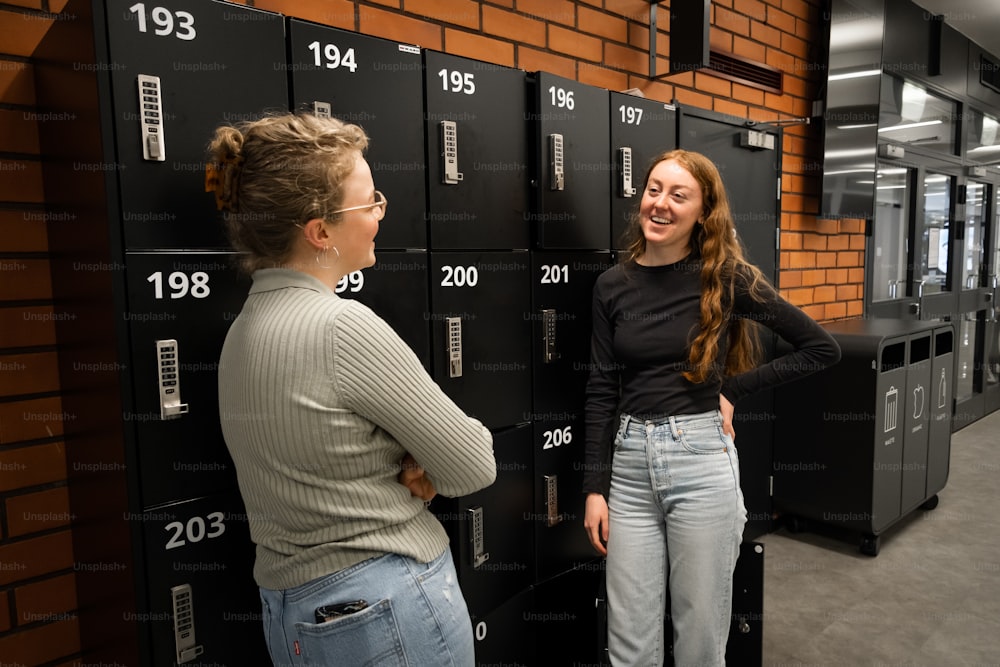 two women standing in front of a row of lockers