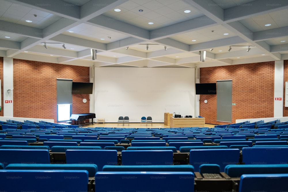 a large auditorium with rows of blue chairs