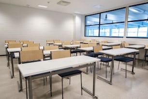 ein Klassenzimmer mit Schreibtischen und Stühlen neben einem großen Fenster