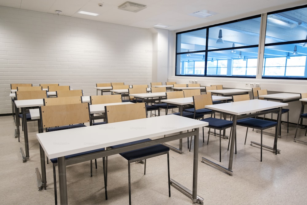 a classroom filled with desks and chairs next to a large window