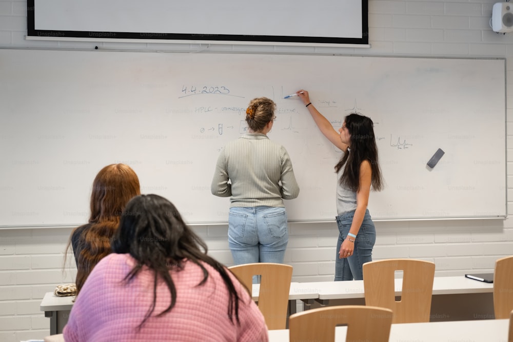 Eine Gruppe von Leuten, die auf ein Whiteboard schreiben