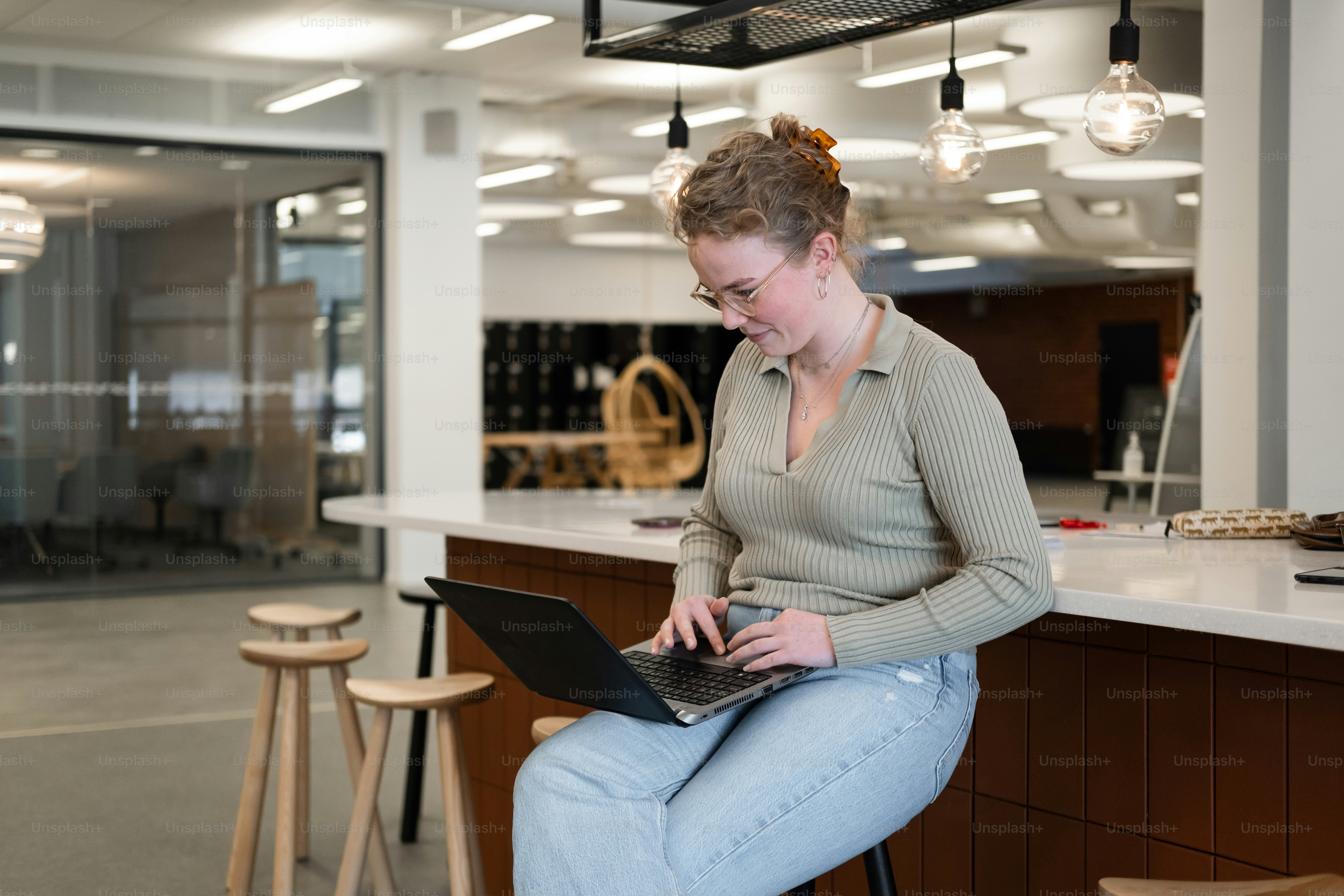 a woman sitting on a stool using a laptop