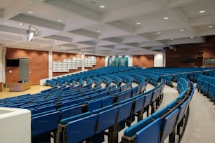 a large auditorium with rows of blue chairs