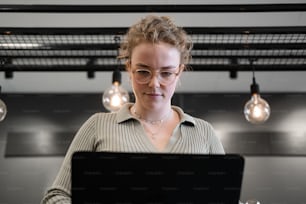 a woman wearing glasses looking at a laptop