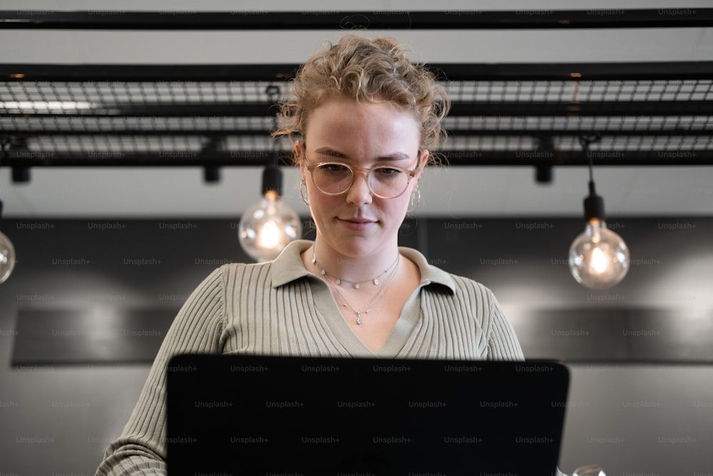 Una mujer con gafas mirando una computadora portátil