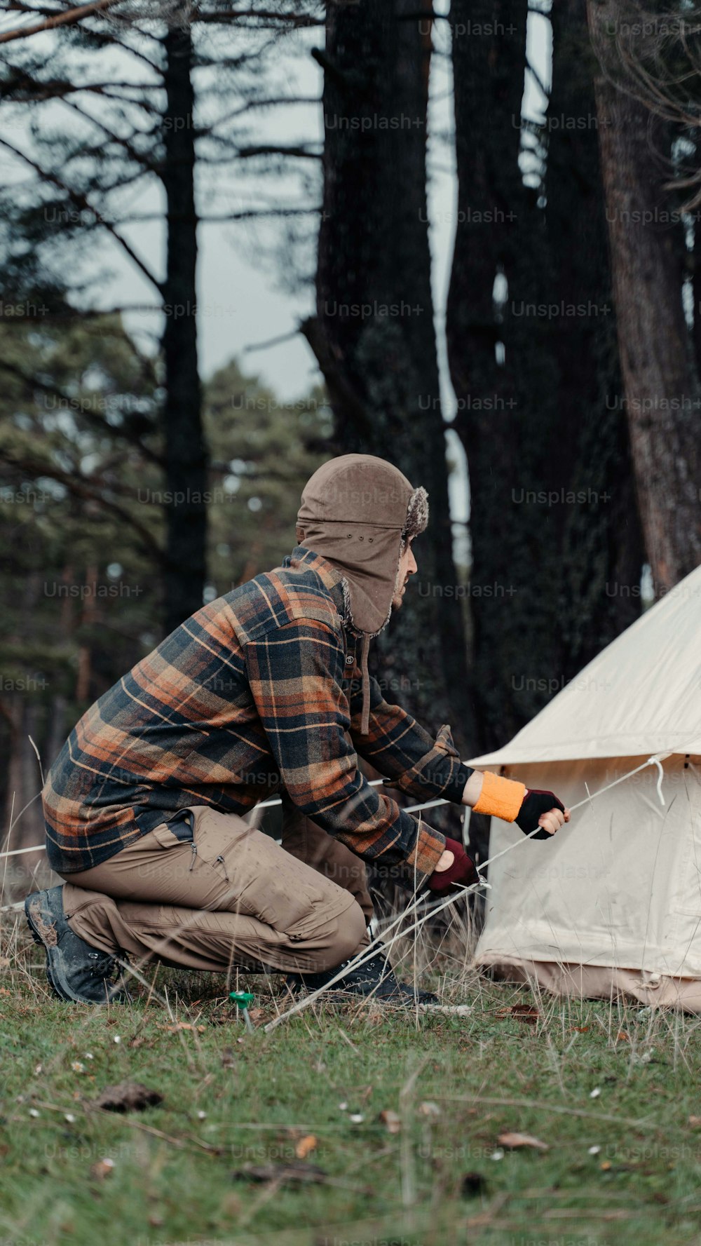 a man kneeling down next to a tent
