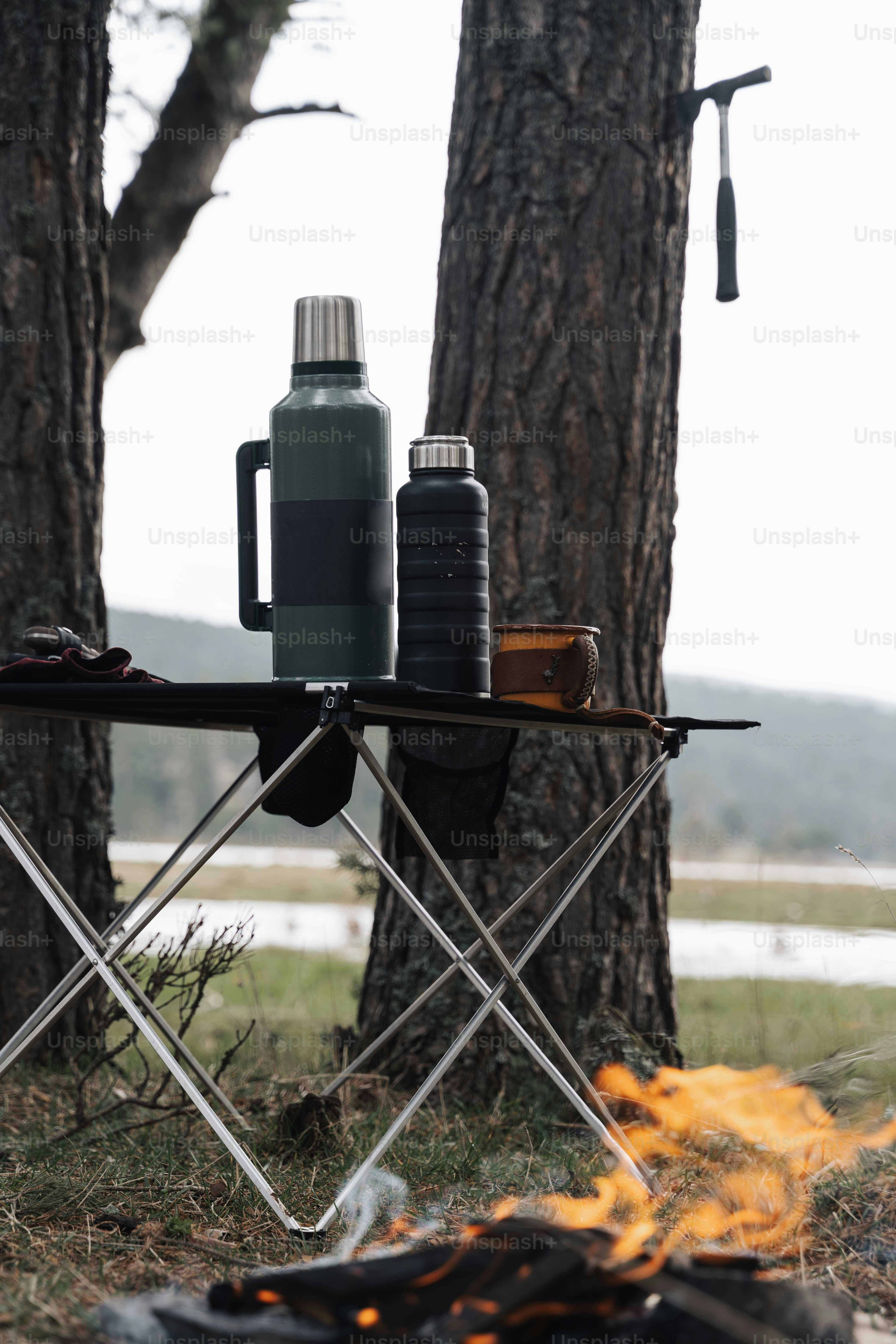 a camping table with a bottle of water next to a campfire