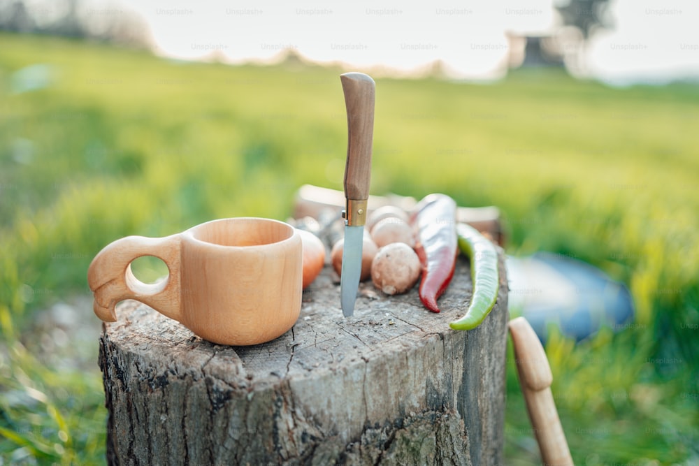 a wooden stump with a knife and a cup on it