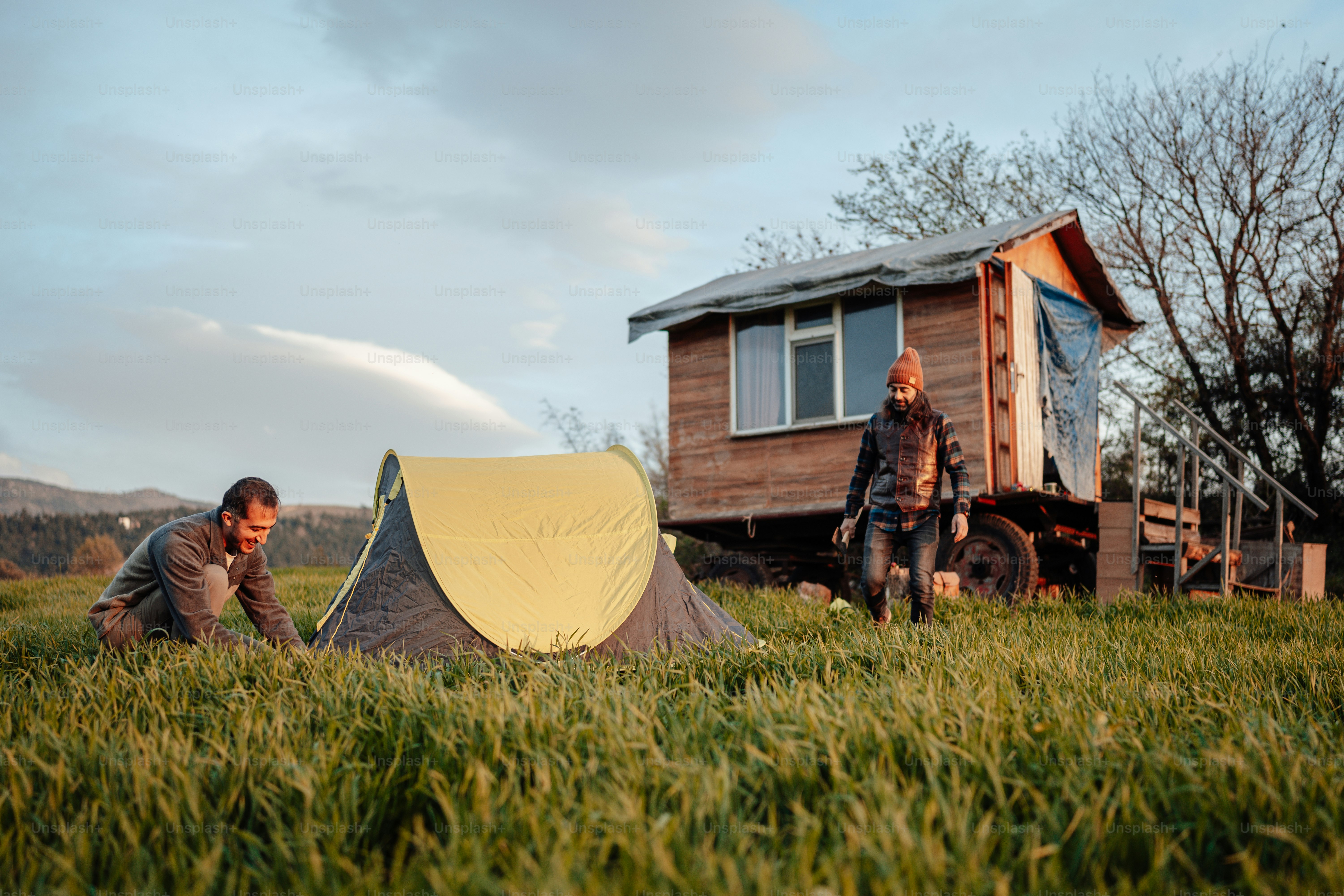 a man and a woman setting up a tent in a field
