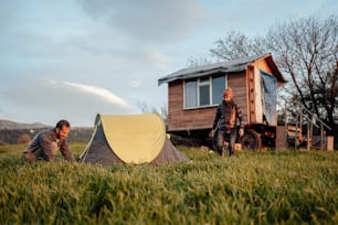 a man and a woman setting up a tent in a field