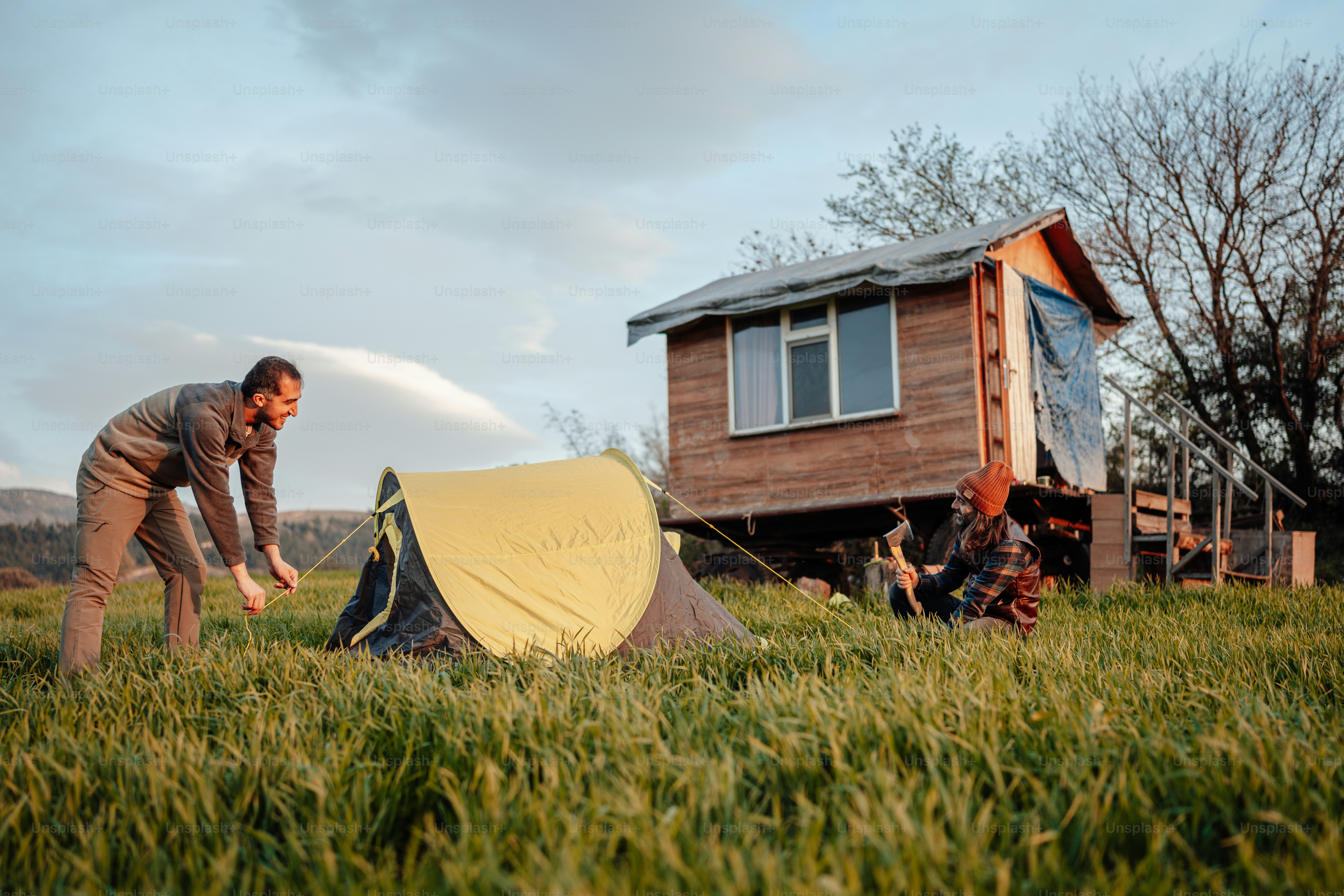 Ein Mann steht neben einem Zelt auf einer saftig grünen Wiese