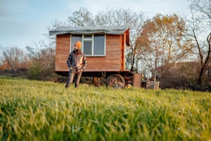 uma pessoa em pé na frente de uma pequena cabine de madeira
