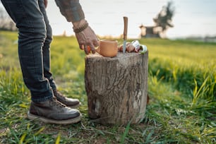 a person standing next to a tree stump holding a cup