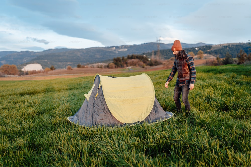 um homem de pé ao lado de uma tenda em um campo