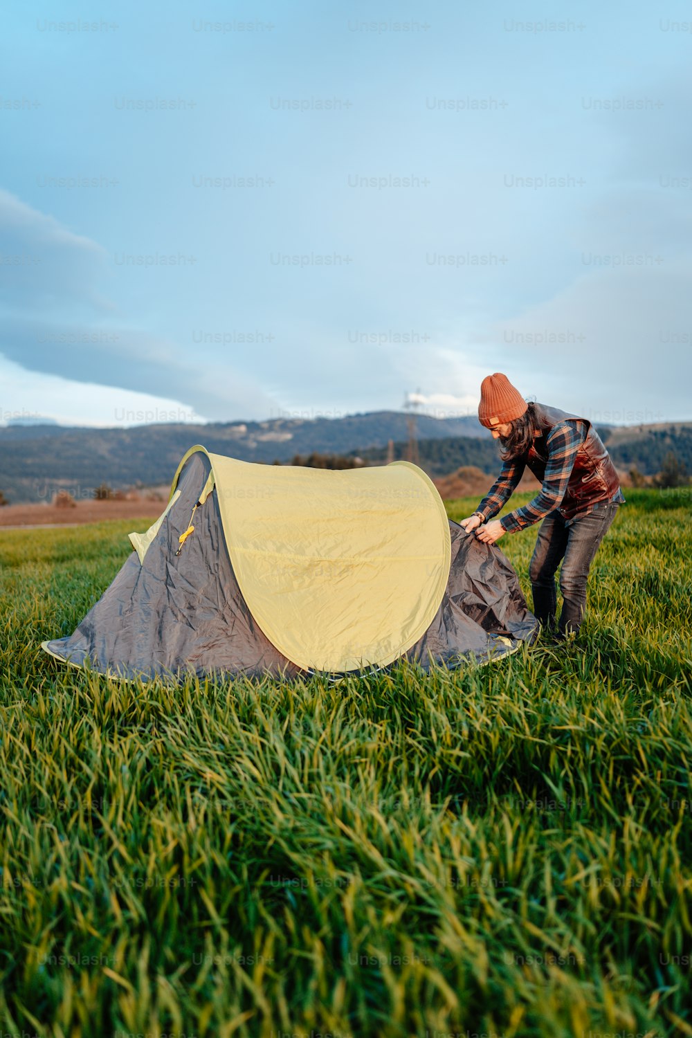 a man is setting up a tent in the grass