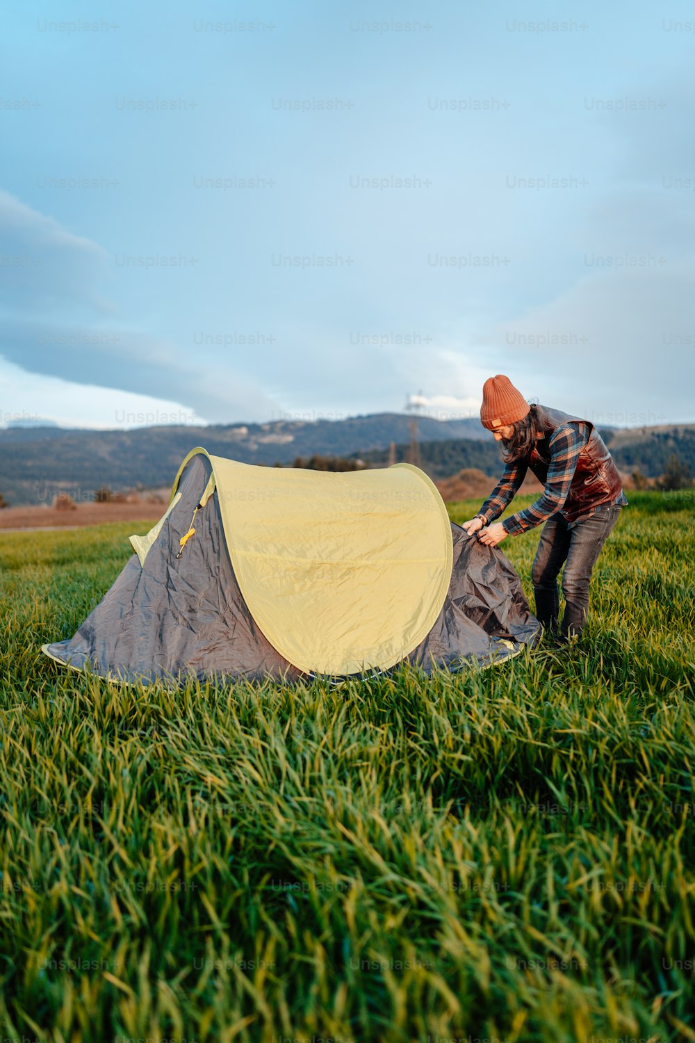 Un homme monte une tente dans l’herbe