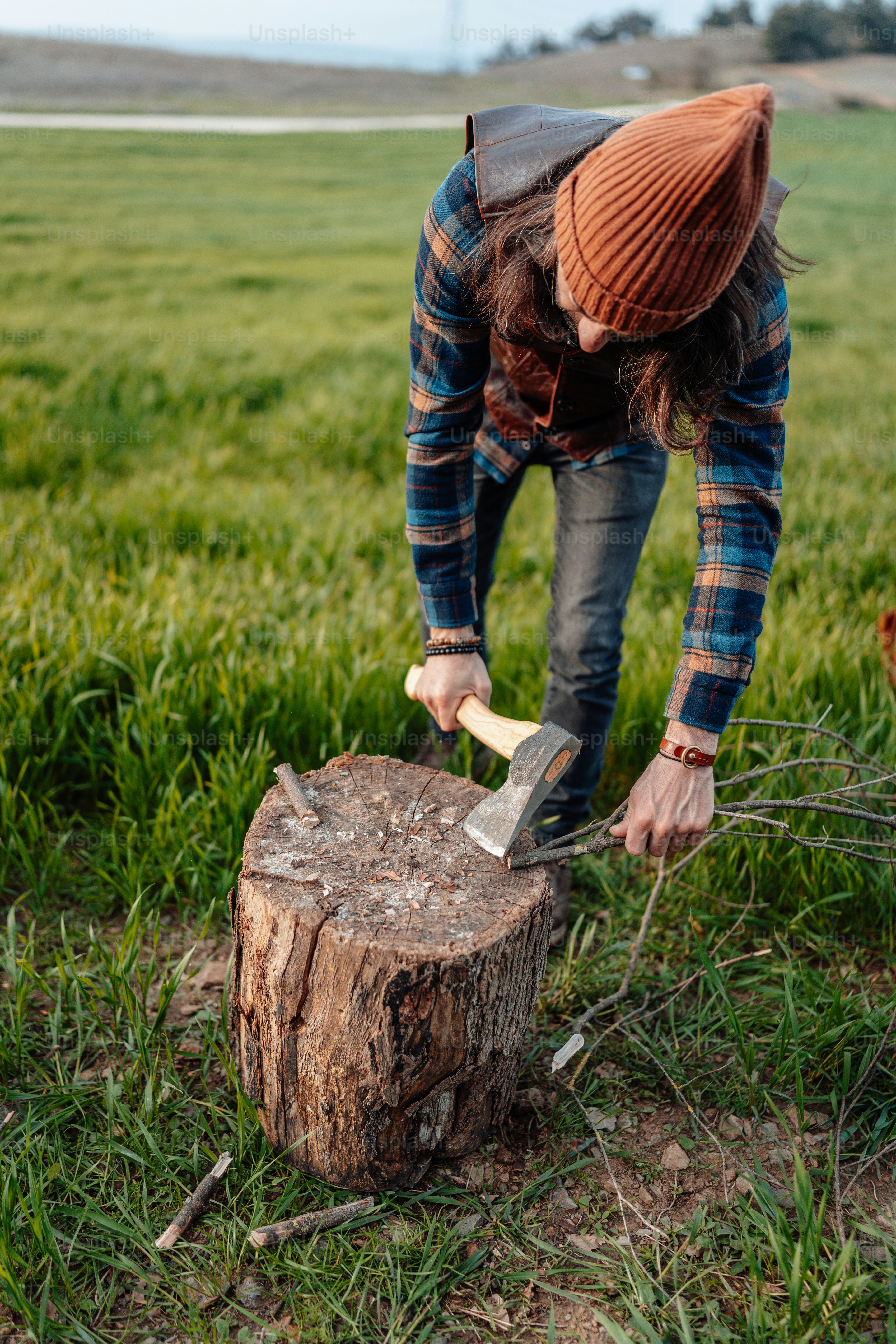 a man in plaid shirt chopping a tree stump
