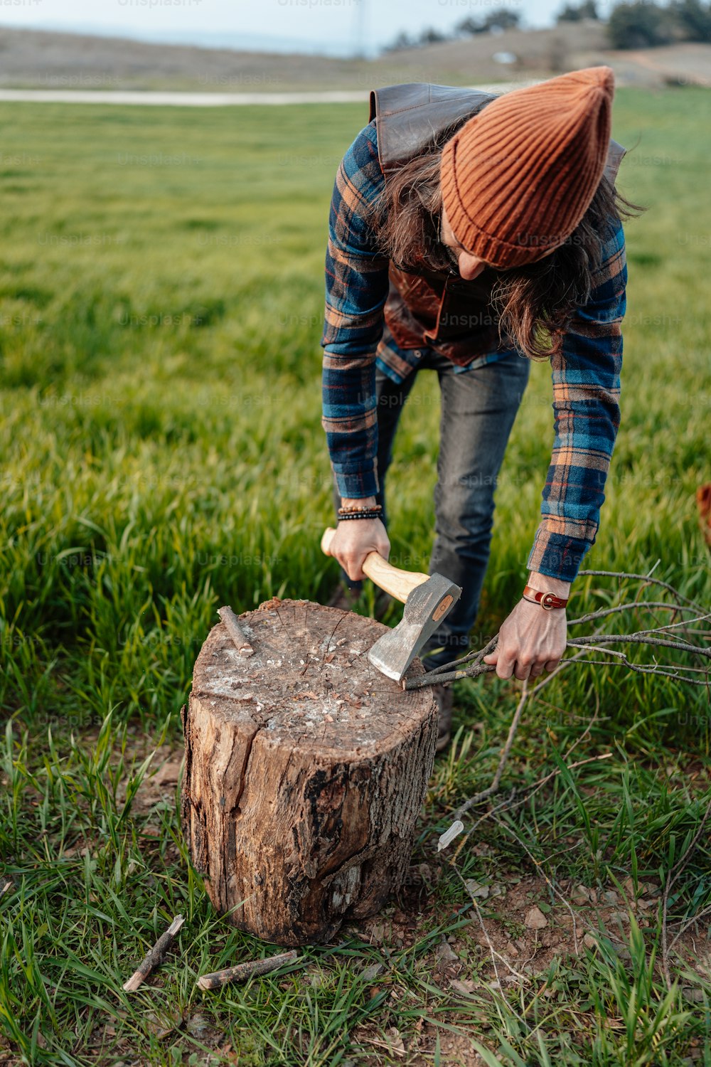 a man in plaid shirt chopping a tree stump