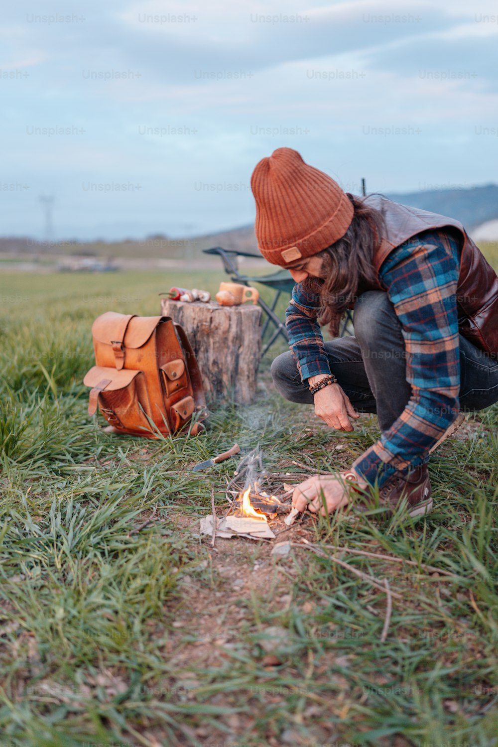 a person kneeling down next to a campfire