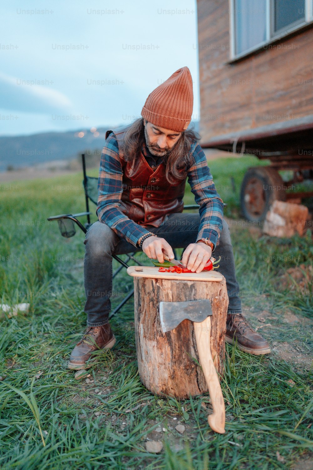 a man sitting on top of a tree stump cutting a piece of wood
