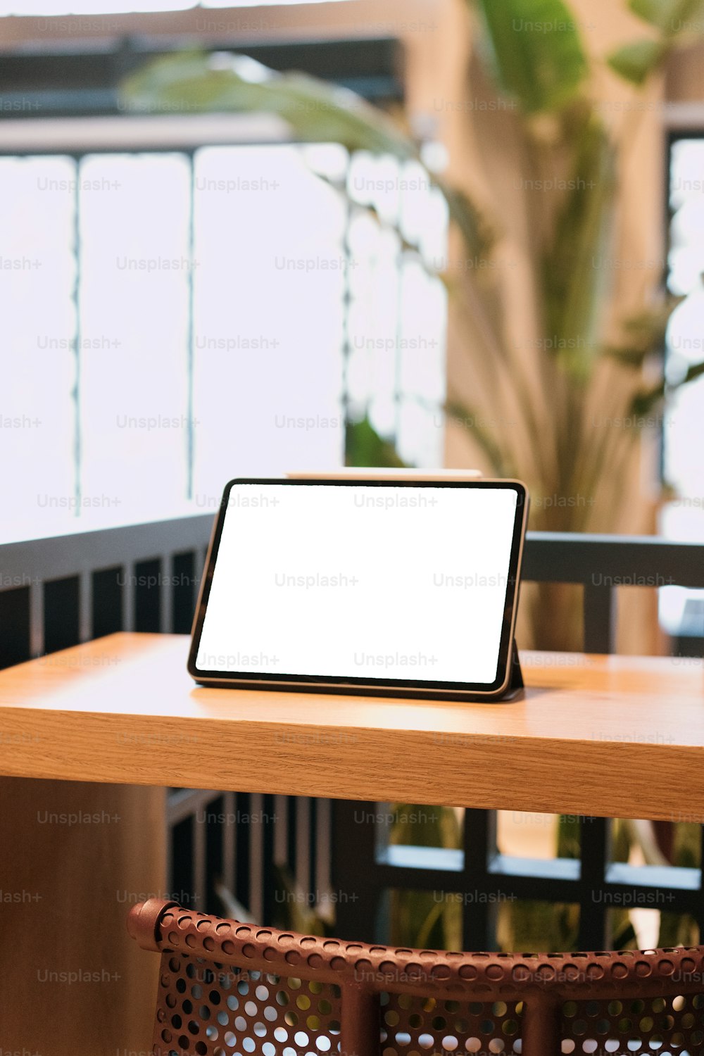 a tablet on a table with a plant in the background