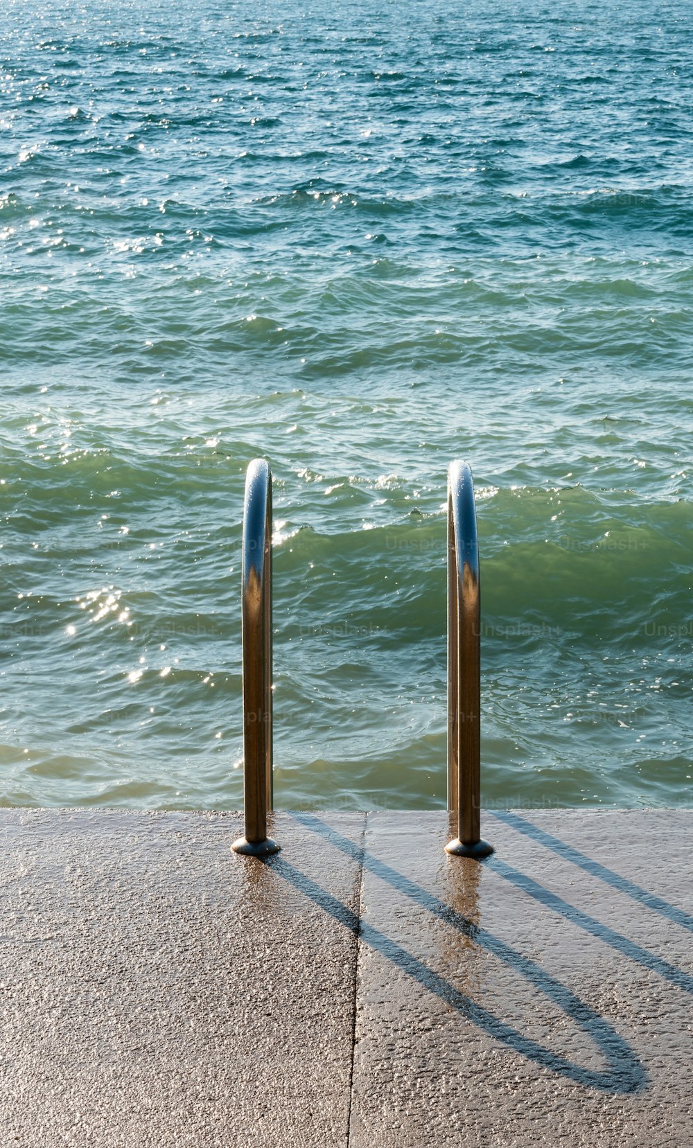 um par de postes de metal sentados ao lado de um corpo de água