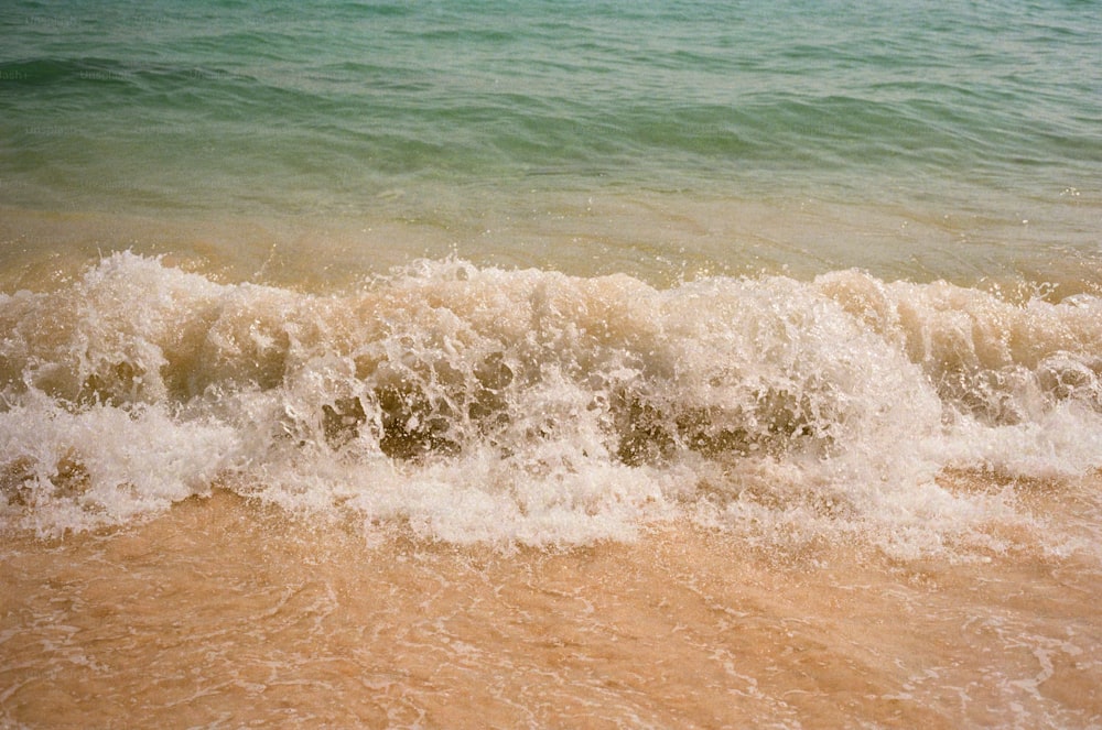 a wave is coming in to the shore of the beach