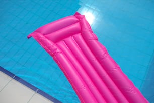 Una grande piscina gonfiabile rosa galleggia in una piscina