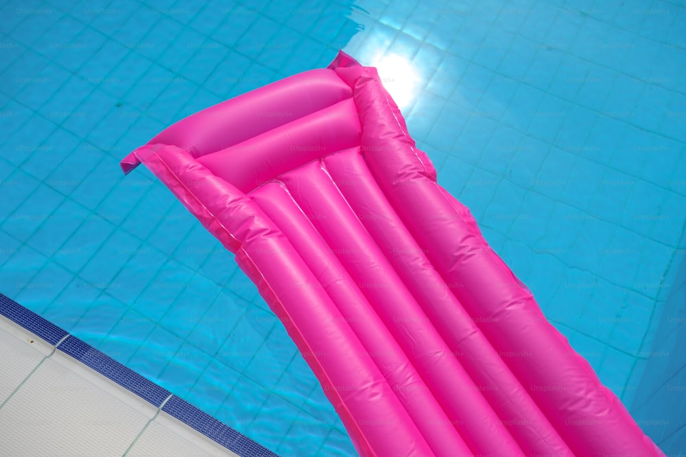 Une grande piscine gonflable rose flotte dans une piscine