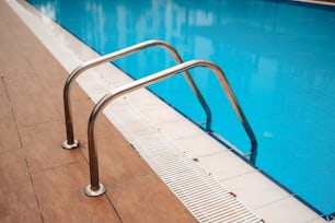a metal hand rail next to a swimming pool