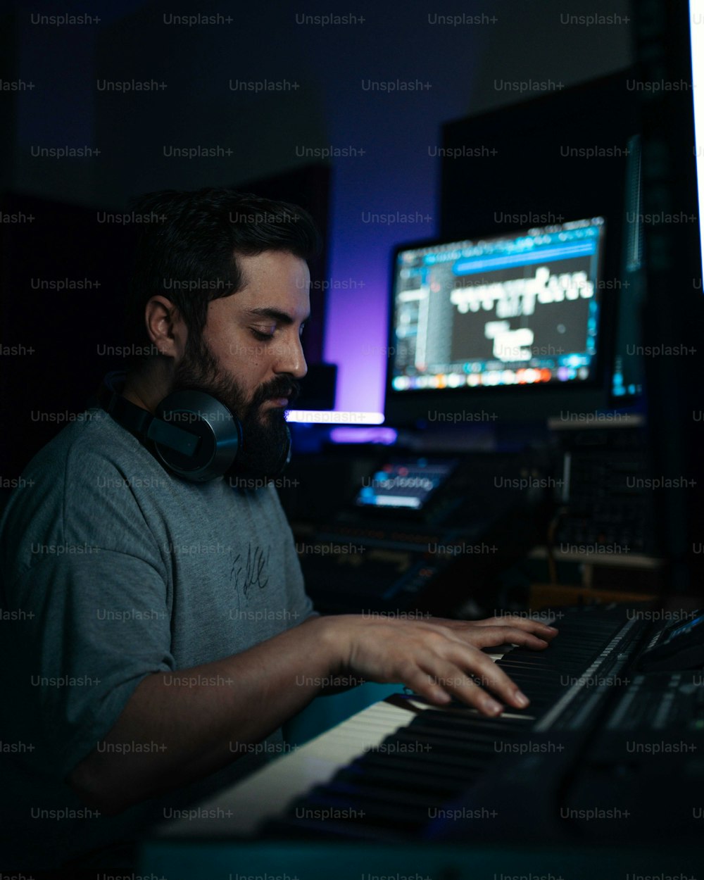 um homem sentado em um teclado na frente de um monitor