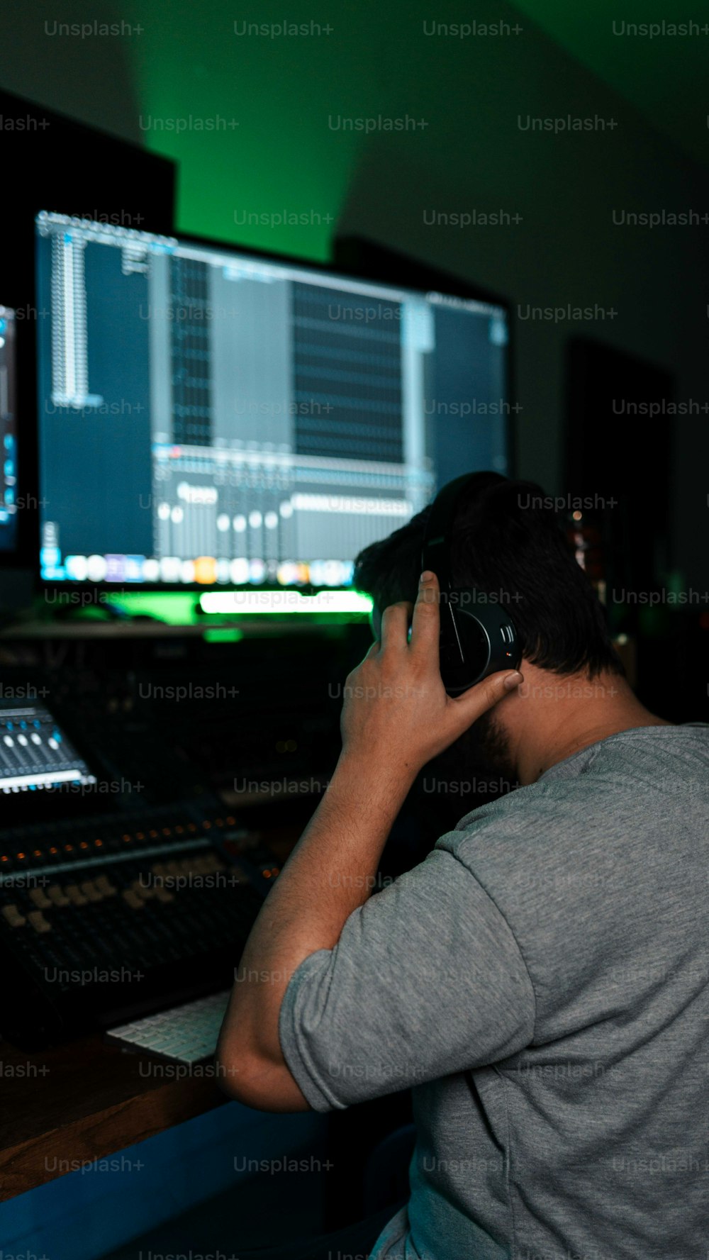 a man sitting in front of a mixing desk talking on a cell phone