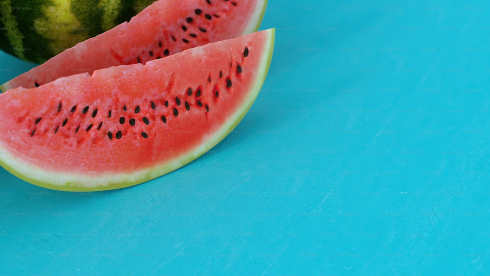 dois pedaços de melancia em uma superfície azul
