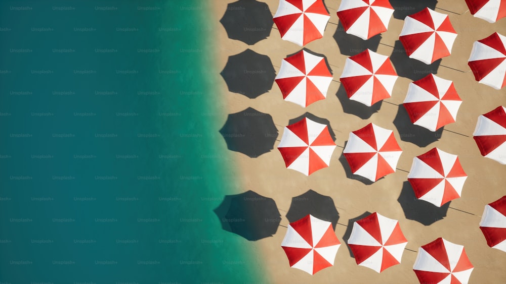 a group of red and white umbrellas on a beach