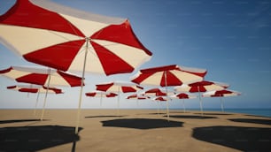 Una hilera de sombrillas rojas y blancas sentadas en la parte superior de una playa de arena
