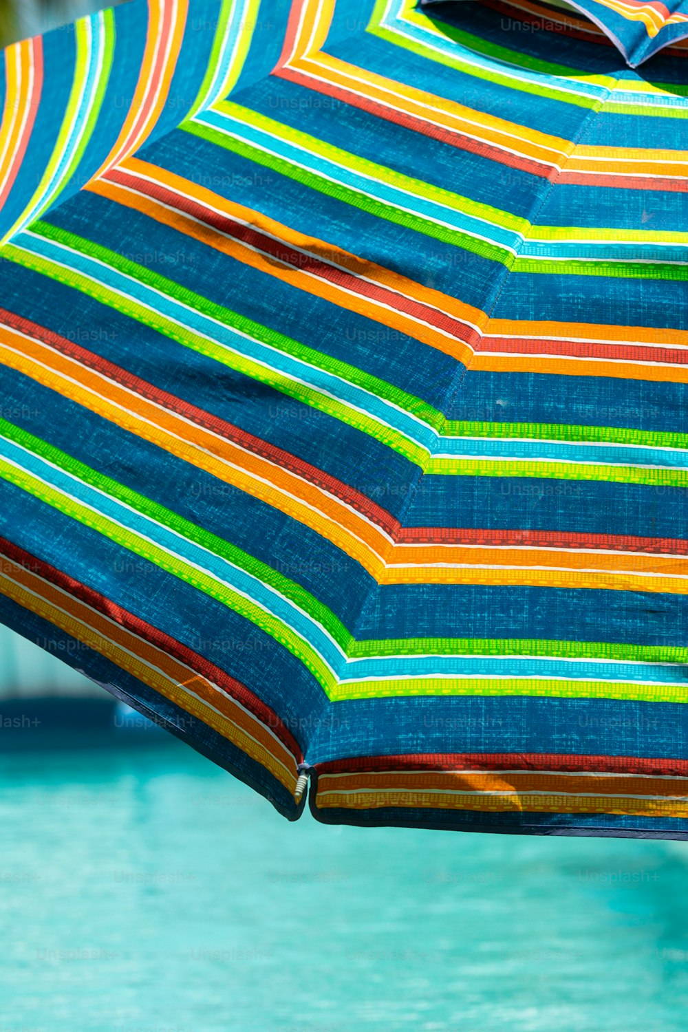 a multicolored umbrella sitting next to a pool